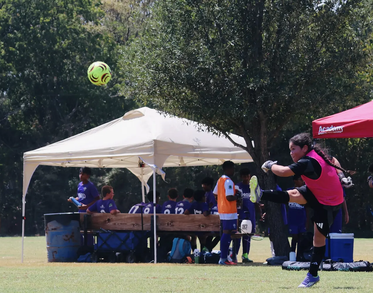 Youth soccer player striking through the ball during a match